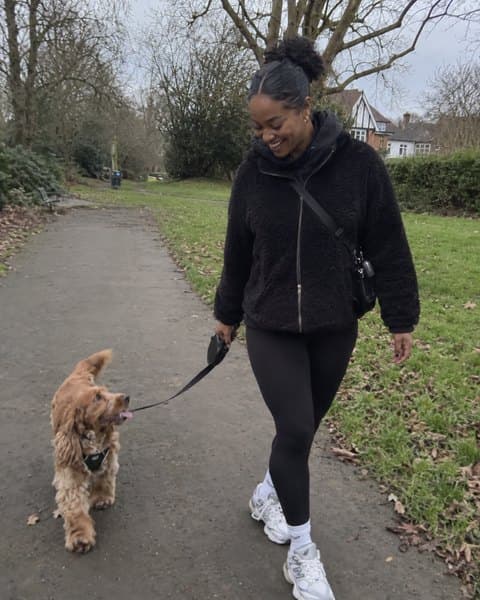 Aisha walking her small dog along a path near home.